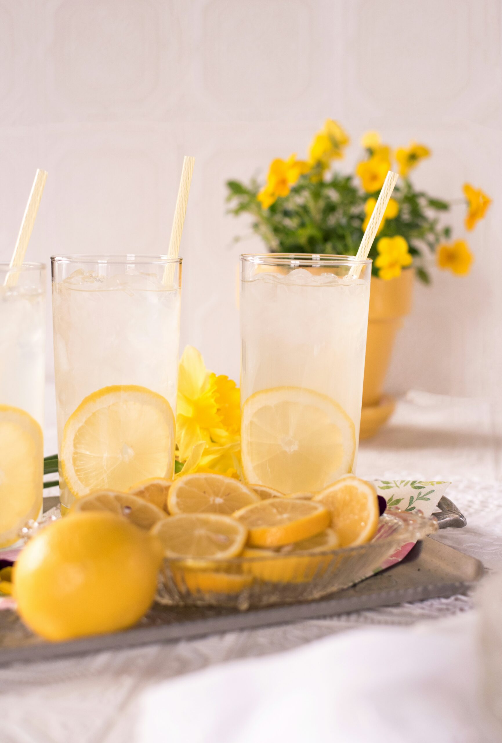 pitcher of lemonade on a table with lemons and flowers