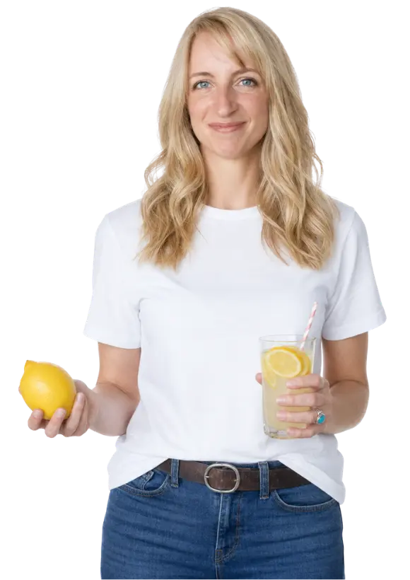 Lizzy Joy, author and coach holds a lemon and a glass of lemonade.